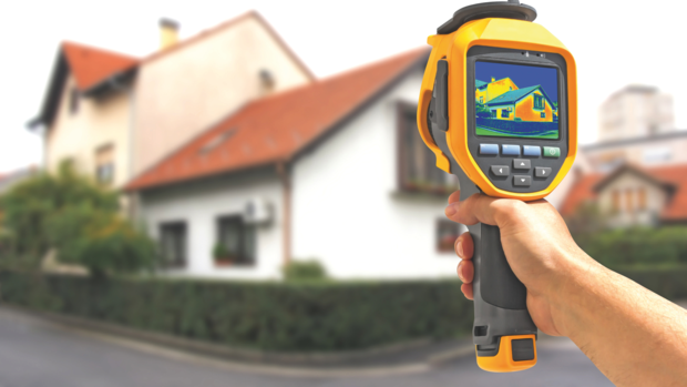 Wärmemessgerät wird auf Haus gerichtet, um Wärme an der Fassade zu messen