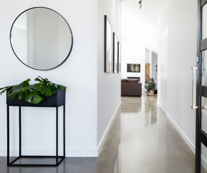Moderner Wohnungsflur mit breitem Gang, weißen Wänden, rundem Spiegel 